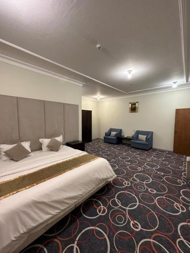 a hotel room with a large bed and two chairs at اجنحة ارتياد للشقق المخدومه in Abha