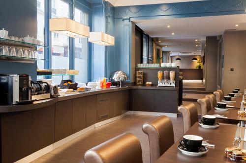 a restaurant with a long counter with chairs and tables at Appia La Fayette in Paris