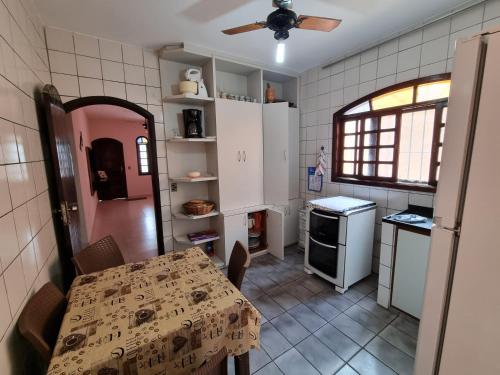 a kitchen with a table and a dining room at Casa com piscina in Bertioga