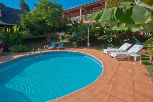 a swimming pool with chaise lounges and chairs near a house at Hotel Posada La Sorgente in Puerto Iguazú