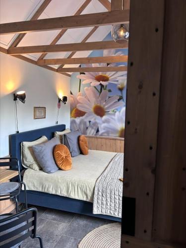 a bedroom with a bed with a flower painting on the wall at Bed en Brochje De Oase in Sweagerbosk