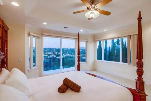 a bedroom with a bed with a ceiling fan and windows at Villa Andalusia 6BR 5BA Luxury Jacuzzi Views and Games in Escondido