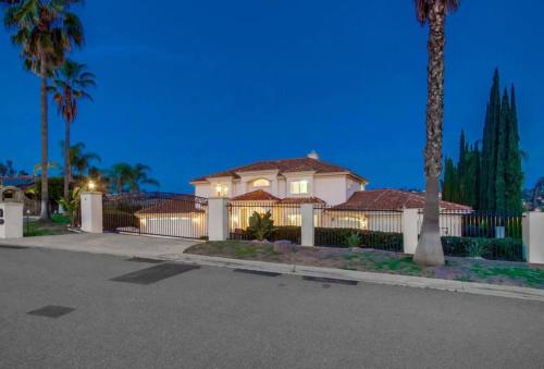 a house with a fence and palm trees at night at Villa Andalusia 6BR 5BA Luxury Jacuzzi Views and Games in Escondido