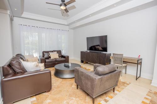 a living room with leather furniture and a flat screen tv at The Atrium Resort in Grace Bay