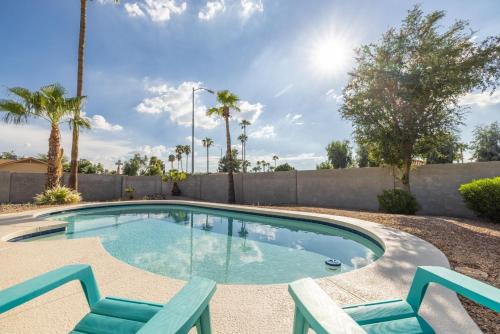 a swimming pool with two chairs and a fence at Scottsdale on 64th in Scottsdale