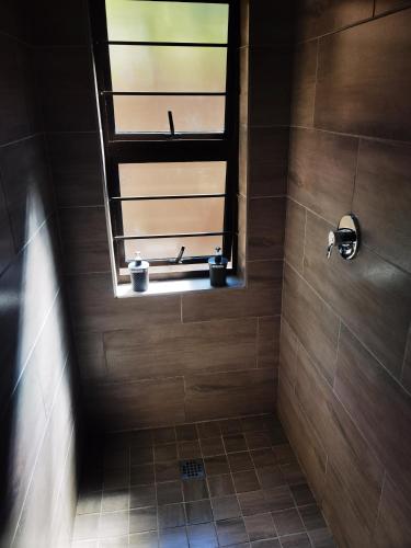 a bathroom with a shower with a window at Calla—Cottage in Ballito