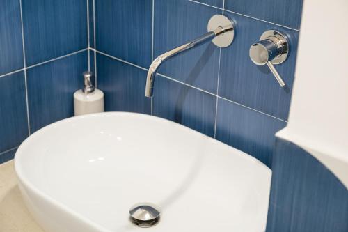 a white toilet in a bathroom with blue tiles at Sud Est 13 in Putignano