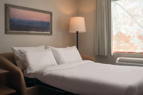 a bedroom with a bed with white pillows and a window at Fairfield by Marriott Inn & Suites Cullman in Cullman