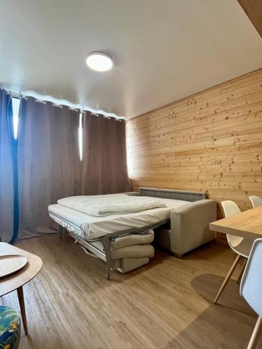 un lit dans une chambre avec un mur en bois dans l'établissement T2 avec Parking - Centre station - SUPER BESSE, à Besse-et-Saint-Anastaise