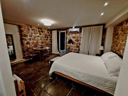 a bedroom with a white bed and a brick wall at Blue Shutter Garden Studio in Komiža