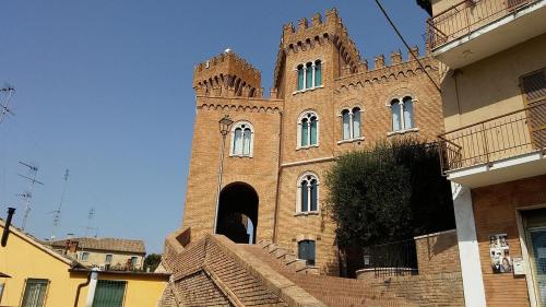 a large brick building with a clock tower with stairs at Relais Verde Casa in Trecastelli