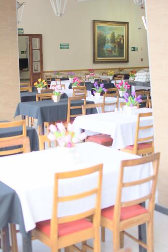 a dining room with white tables and wooden chairs at Presidente Hotel in Poços de Caldas