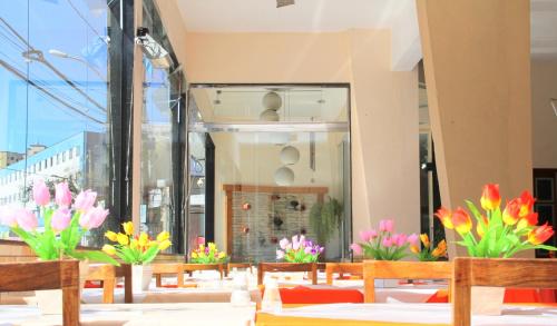 a restaurant with flowers on tables in front of a window at Presidente Hotel in Poços de Caldas
