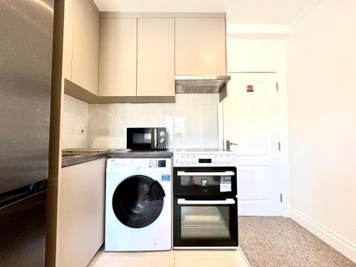a kitchen with a washing machine and a microwave at Spectacular Modern, Private Apartment,15 Mins To Central London in Hendon