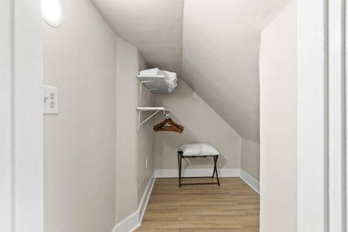 a white hallway with a chair and a stair case at The Luxe Hot Tub Private Bar 12 Min to Horse Park in Georgetown