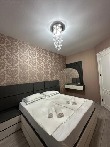 a bedroom with a bed with white sheets and a chandelier at Home M&M in Kutaisi