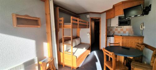 Cette petite chambre comprend des lits superposés et une table. dans l'établissement Résidence Etoile - Studio pour 4 Personnes 374, à Aime La Plagne