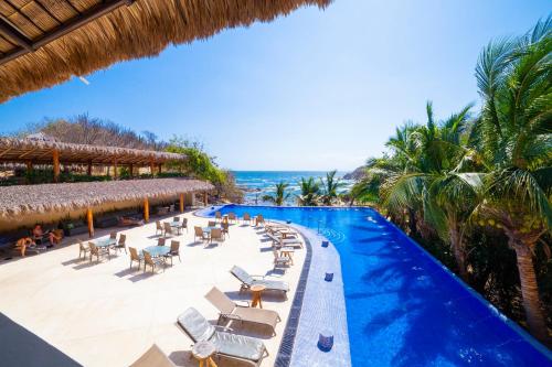 a resort with a pool and chairs and the ocean at Coral Blue Huatulco All Inclusive in Santa Cruz Huatulco