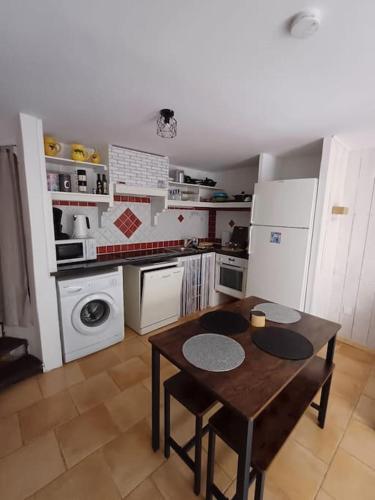 une cuisine avec une table et une cuisine avec des appareils électroménagers blancs dans l'établissement maison de village, à Montferrat