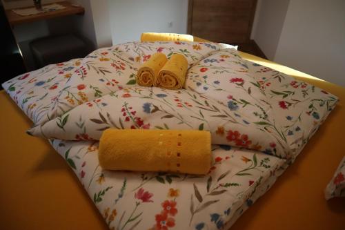 a bed with a comforter with a towel and two yellow rolled towels at Landhaus-Appartements Warraich in Schladming