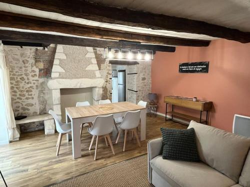 - un salon avec une table, des chaises et un piano dans l'établissement Gîte - Comme à la maison, à Saint-Martin-la-Rivière