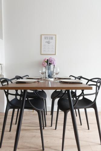a wooden dining table with black chairs and flowers on it at Appartement de l'UNESCO de Blaye- Spacieux & confort - 2 chambres in Blaye