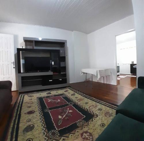 een woonkamer met een televisie en een tapijt bij Casa Com 2 quartos, Garagem Ar tv in Foz do Iguaçu