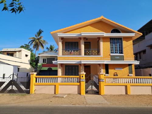 a yellow house with a fence in front of it at Rooms in Orange Homestay in Thanjāvūr