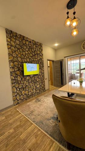 a living room with a stone wall with a tv on it at Qubada gunluk dağ kiraye evi in Quba