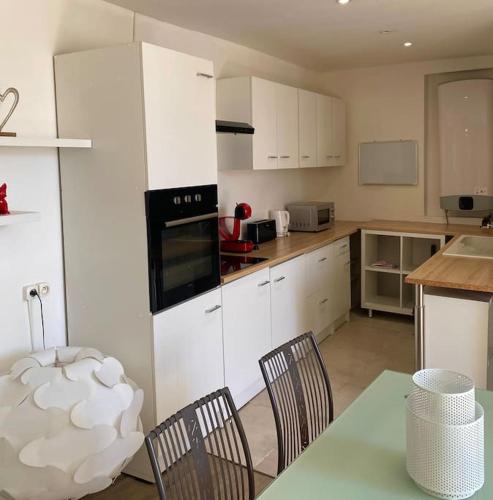 une cuisine avec des armoires blanches et une table et des chaises dans l'établissement Idéal pour un court séjour, à Caveirac