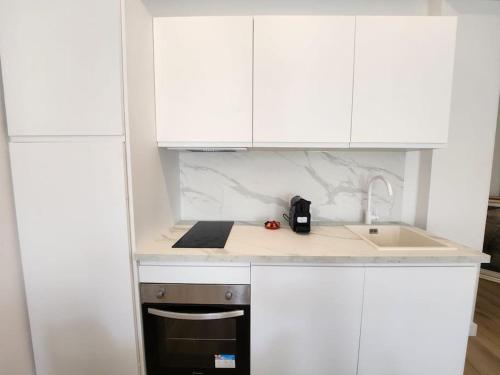 una cucina con mobili bianchi, un lavello e una stufa di Nice Fac St Jean D'Angely a Nizza