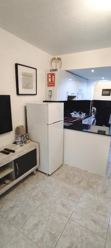 a kitchen with a white refrigerator and a tv at Castillo Mar 95 in Caleta De Fuste