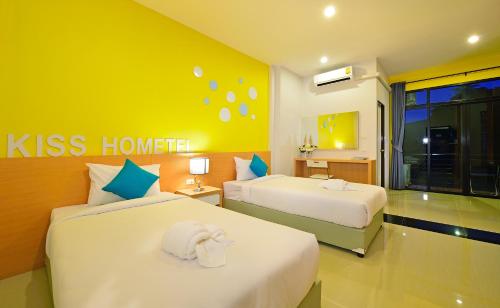 a hotel room with two beds and a yellow wall at Kiss Hometel in Ao Nang Beach