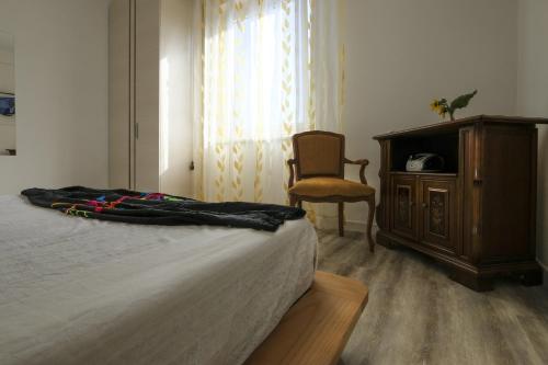 a bedroom with a bed and a chair and a dresser at BB Il benvenuto in Loreto