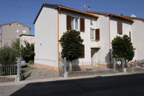 a white house with a fence next to a street at BB Il benvenuto in Loreto