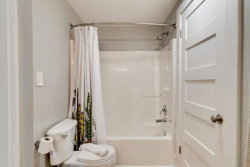 a white bathroom with a toilet and a shower at East Nash Retreat- Sleeps 10, Yard, Walk to Bars! in Nashville