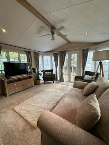 a living room with a couch and a flat screen tv at 56 Main Park Caravan Hire Lillardsedge Holiday Park Jedburgh in Jedburgh