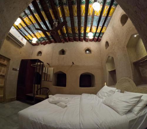 a bedroom with a large white bed with a ceiling at كمكان kmkan in Bahlāʼ