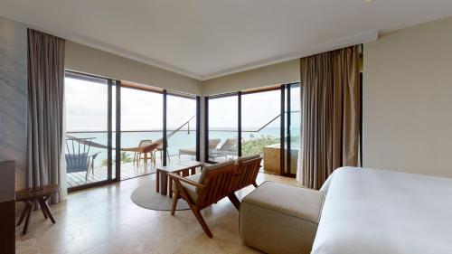 a bedroom with a bed and a desk and a balcony at Hotel Xcaret Arte - All Parks All Fun Inclusive - Adults Only in Playa del Carmen