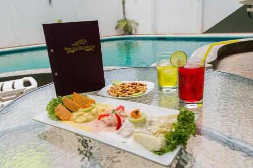 a plate of food on a table with a drink at Hotel Jhor Bush in Pucallpa