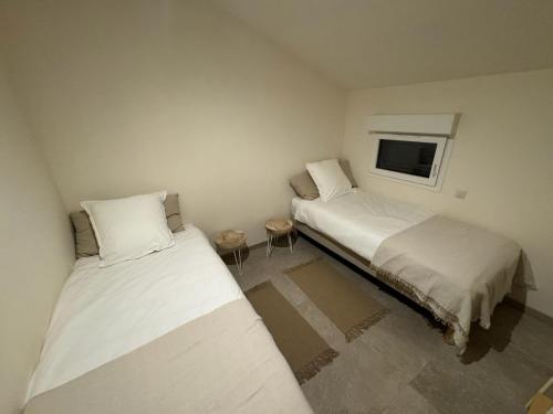 une chambre avec deux lits et une télévision au mur dans l'établissement Charmante maison en pierre vue mer et piscine privée, à Cuttoli-Corticchiato