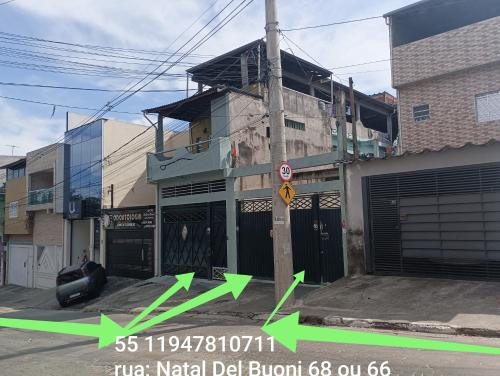 グアルーリョスにあるHOSTEL FAMÍLIA quartos privado próximo aeroporto Int Guarulhos SP TÁXI 24 hrsの緑の矢印が付いた市街地の通りにある建物