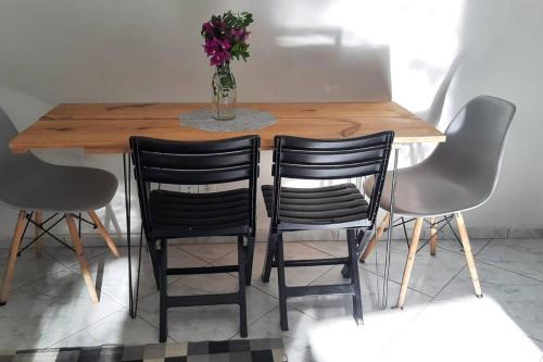 a wooden table with four chairs and a vase with flowers at Casa espaçosa bem localizada em Maricá! in Maricá