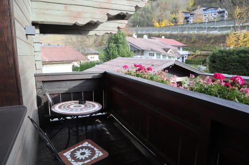 a balcony with a table and a chair and flowers at Landhaus-Appartements Warraich in Schladming