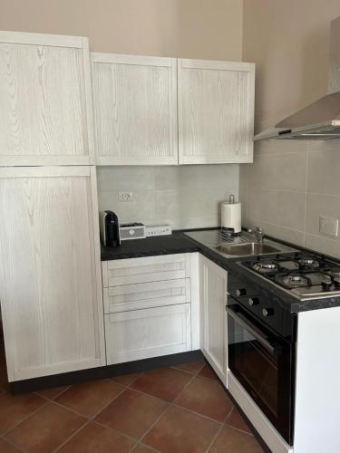 a kitchen with white cabinets and a stove top oven at Residenze Ponte in Ponte