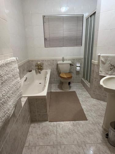a bathroom with a tub and a toilet and a sink at Bult-Op1 in Bloemfontein