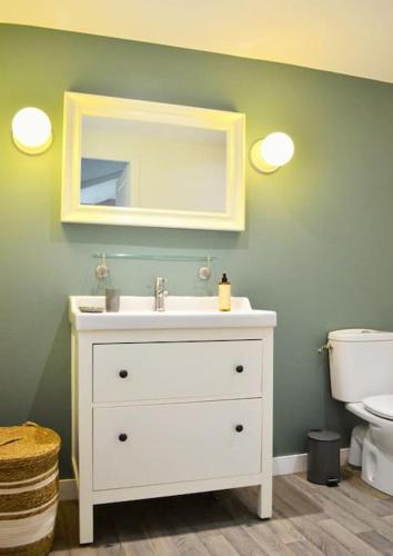 une salle de bain avec un lavabo et un miroir et des toilettes dans l'établissement Chalet cosy au cœur de la forêt de Brocéliande, à Beignon
