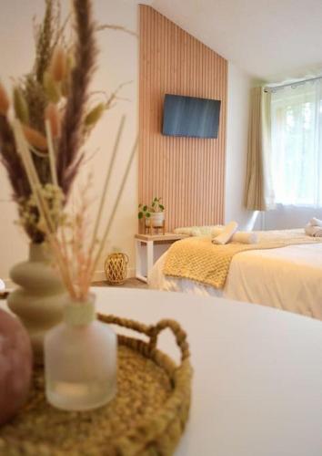 Cette chambre comprend 2 lits et un vase avec des fleurs. dans l'établissement Chalet cosy au cœur de la forêt de Brocéliande, à Beignon