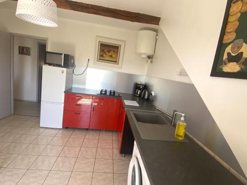 une cuisine avec des armoires rouges et un réfrigérateur blanc dans l'établissement Le Grimaubois, à Hurbache