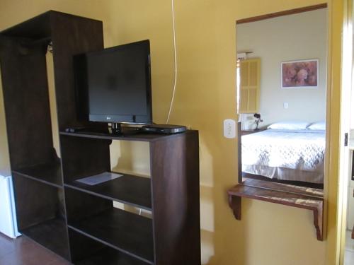 uma TV em um suporte em um quarto com uma cama em Pousada As Relíquias de Minas em Tiradentes